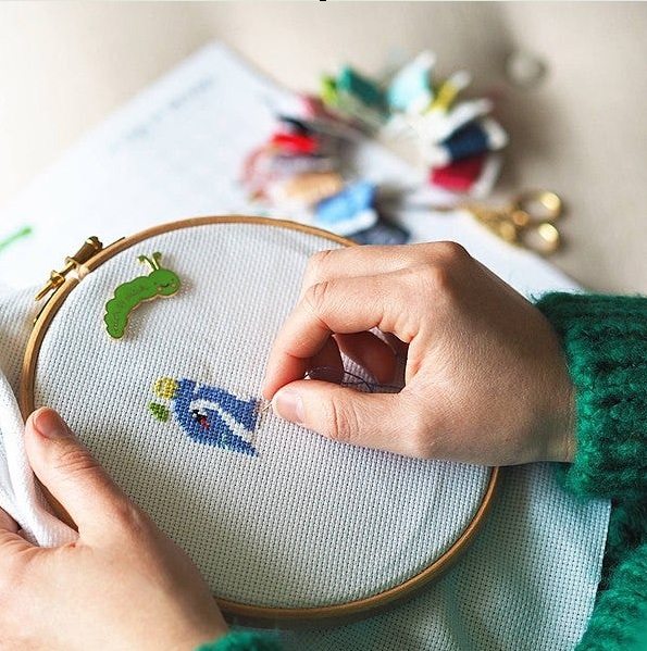 Person engaged in cross-stitch activity